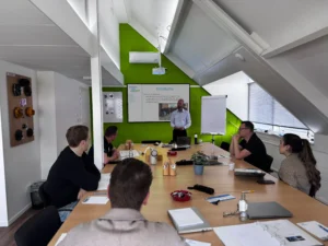 Een groep mensen volgt een beheerderstraining in een moderne vergaderruimte met groene accenten.