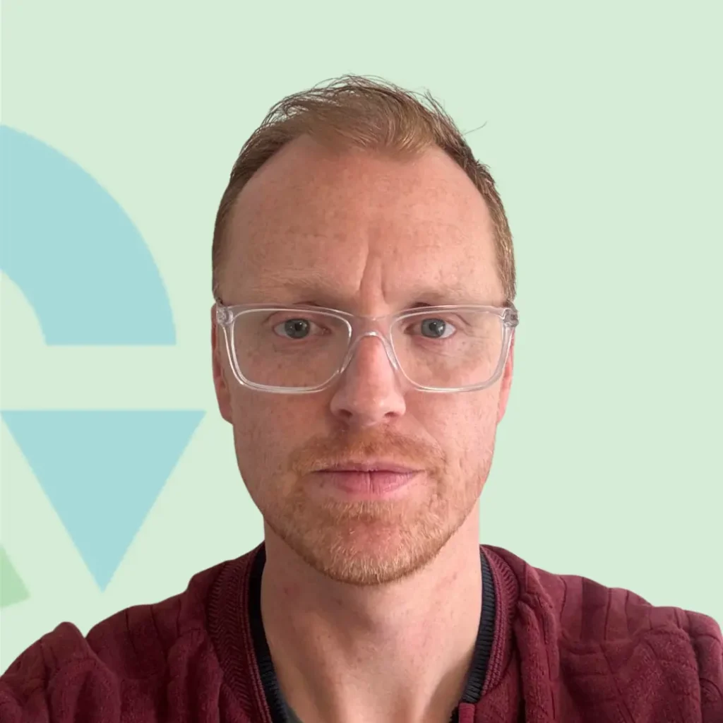Portret van een man met bril en een rode trui tegen een lichtgroene achtergrond.