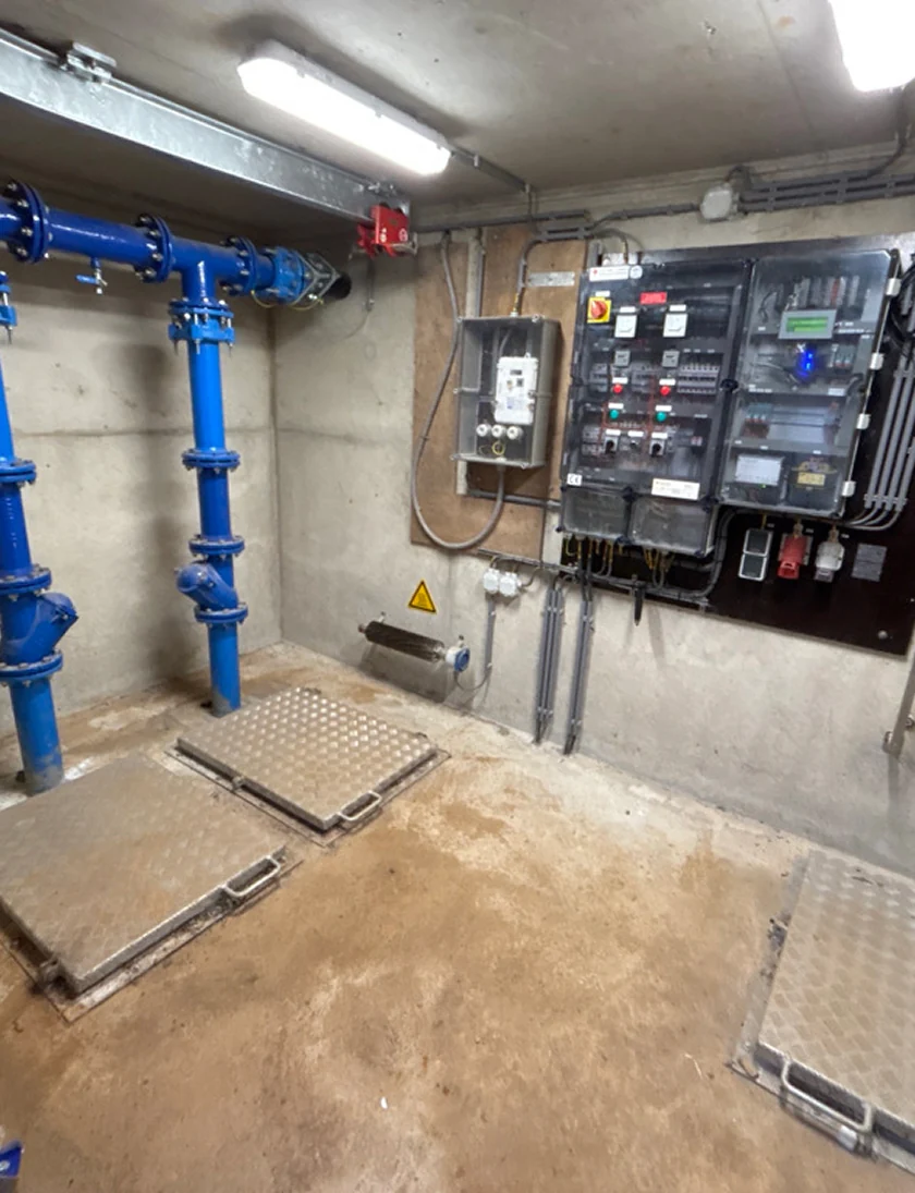 Een technische ruimte met blauwe leidingen en elektrische panelen voor veiligheidskeuringen.