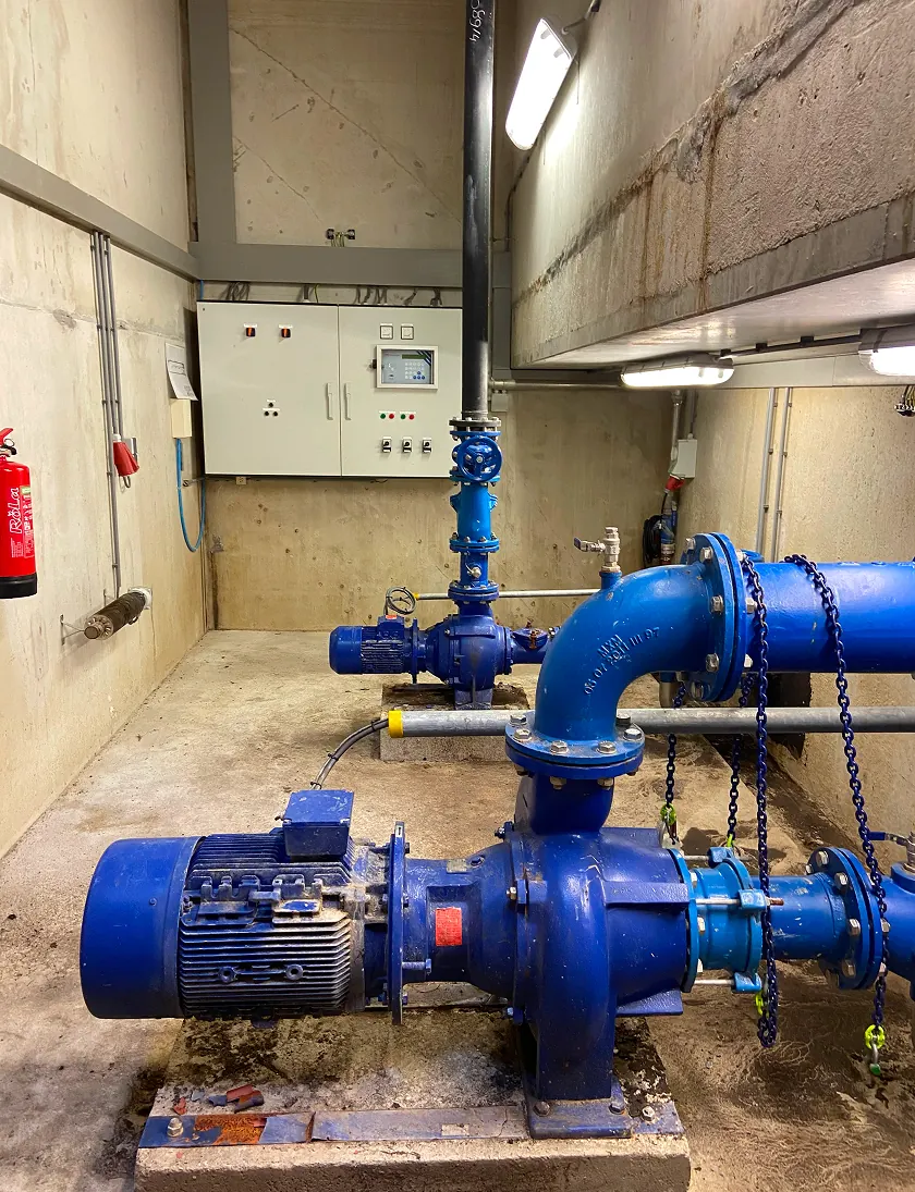 Een industriële installatie met blauwe pompen en leidingen in een technische ruimte.