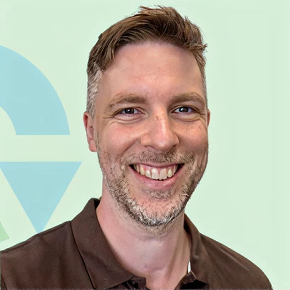 Jelle de Jong staat glimlachend op de foto voor een mintgroene achtergrond.